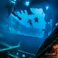 Divers exploring the broken hull of the El Aguila wreck in Roatan