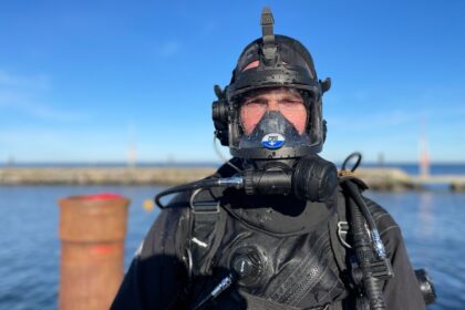 DIVEIN tester wearing the OTS Guardian full face mask on a dock before a cold water dive
