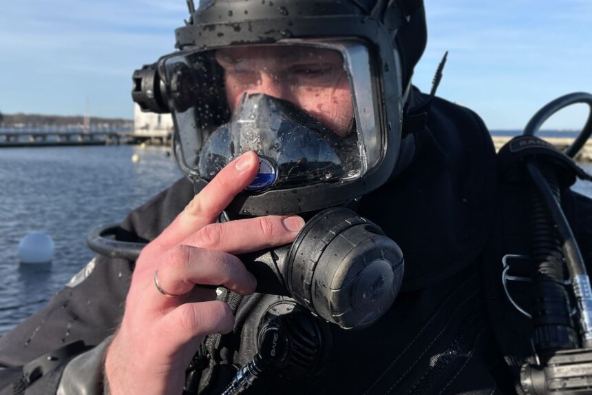 Using The OTS Guardian Purge Button Our tester pressing the purge button on the OTS Guardian full face mask while floating at the surface