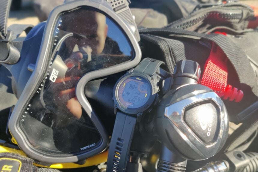 Garmin Descent G1 Solar laid on a dive mask next to a regulator second stage in our test kit