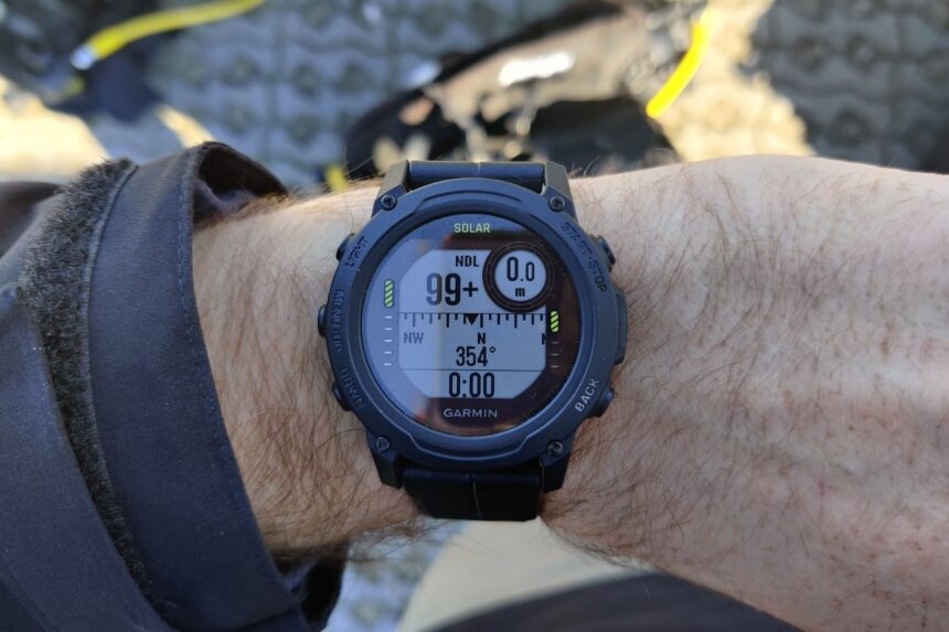 Garmin Descent G1 Solar on our tester's wrist showing 99+ no-decompression time and a compass heading