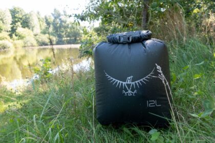 Our tester's Osprey UltraLight 12L dry sack rolled shut and beading water in grass beside a pond