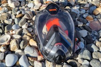 SEAC Unica full face snorkel mask lying face up on a pebble beach