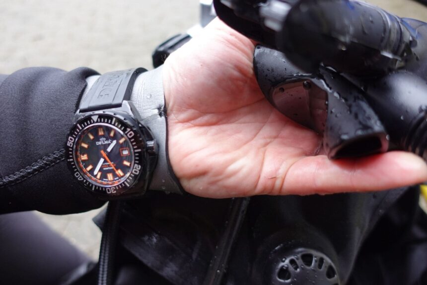 Delma Shell Star Black Tag In Hand Our tester wearing the Delma Shell Star Black Tag while holding wet black dive gear in one hand
