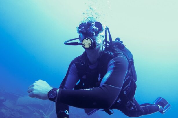 DIVEIN tester finning through blue water in full scuba gear with a black dive watch on the wrist