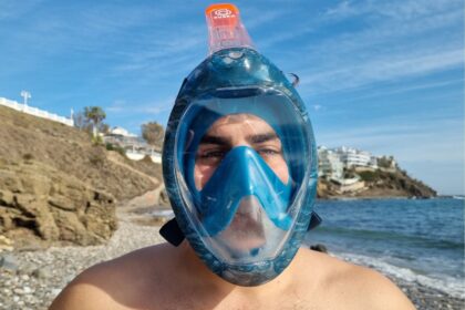 DIVEIN tester wearing the blue Subea Easybreath 500 full face snorkel mask on a pebble beach