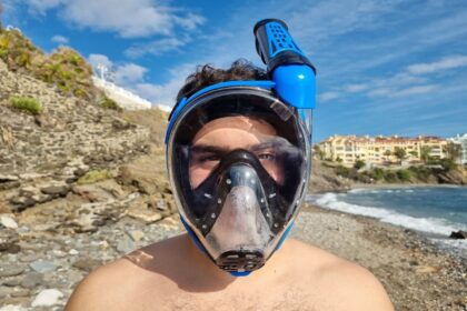Our reviewer wearing the black and blue Cressi Duke full face snorkel mask on a rocky beach