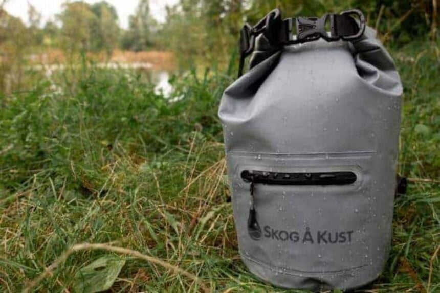 Skog A Kust DrySak Front Pocket Skog A Kust DrySak dry bag beaded with water in grass, showing its zippered outer pocket