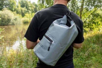 Our tester wearing the Skog Å Kust DrySåk grey dry bag slung across his back beside a lake