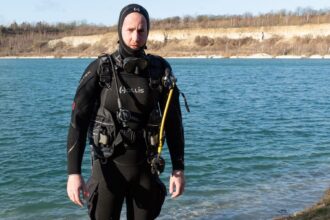 Our tester standing in a cold quarry lake wearing the hooded Hollis Neotek semi-dry suit