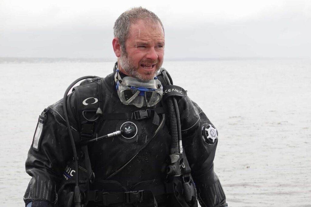 DIVEIN tester Bradley in a drysuit and dive gear with his mask pushed down around his neck after a dive
