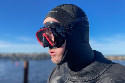 Our tester wearing the Kraken Aquatics mask with its red frame over a black hood, harbour water behind