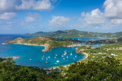 Hilltop view over a sheltered Antigua bay full of moored yachts, with green hills beyond