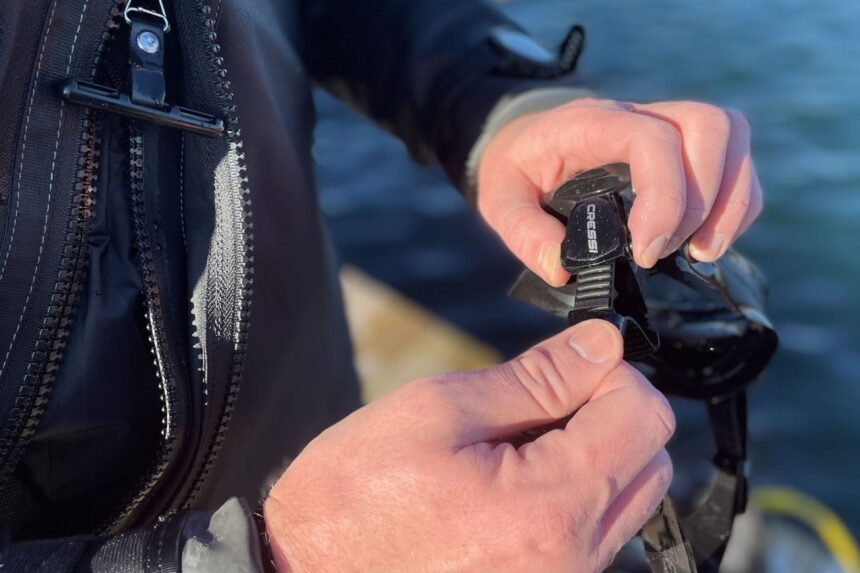 Adjusting the Cressi F1 Micrometric Buckle Our tester adjusting the Cressi F1 mask's micrometric buckle by hand at the water's edge