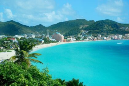 Turquoise bay in St. Maarten with a white sand beach and the town backed by green hills