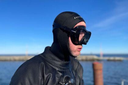 Our tester in a drysuit and hood wearing the Cressi F1 mask, seen in profile before a cold-water dive