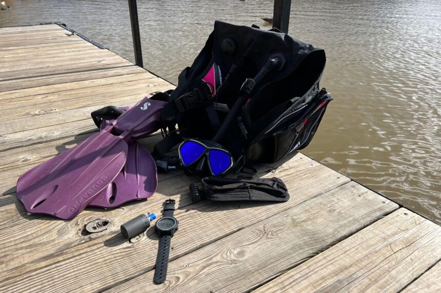 Geo Air And Dive Kit On A Dock Scuba kit laid out on a dock with a BCD, mask, purple fins, the Oceanic Geo Air and its transmitter