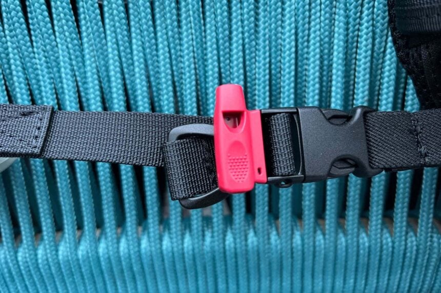 Close-up of the TUSA Tina's waist strap with a pink whistle clipped beside the quick-release buckle