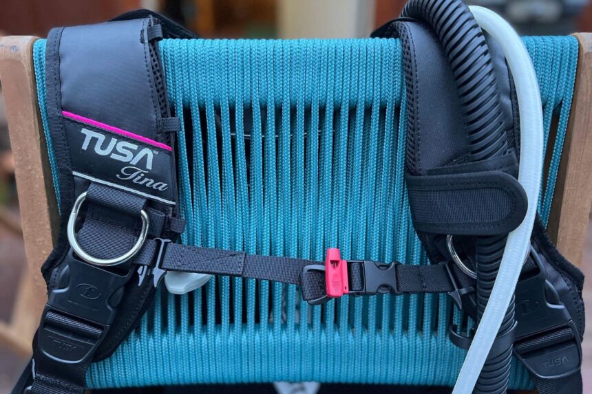 TUSA Tina BCD resting on a wooden chair, showing its shoulder harness, waist strap and inflator hose