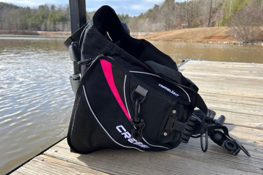 Side view of the Cressi Travelight BCD on a dock, showing its slim back-inflate profile and shoulder strap