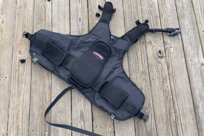 Cressi Travelight BCD laid flat on a wooden dock, showing its back-inflate harness, pockets and shoulder straps