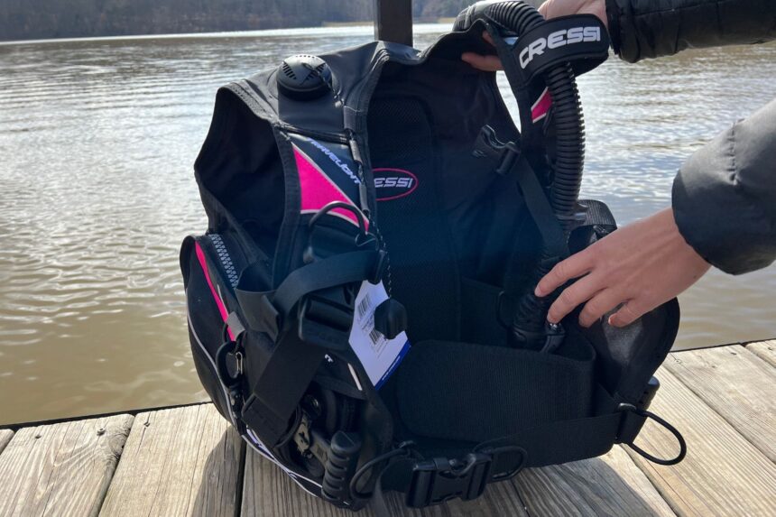 Our tester opening the Cressi Travelight BCD on a dock to show the chest strap, cummerbund and inflator hose