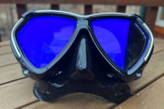 TUSA Paragon dive mask with blue mirrored lenses and a black frame on a wooden table