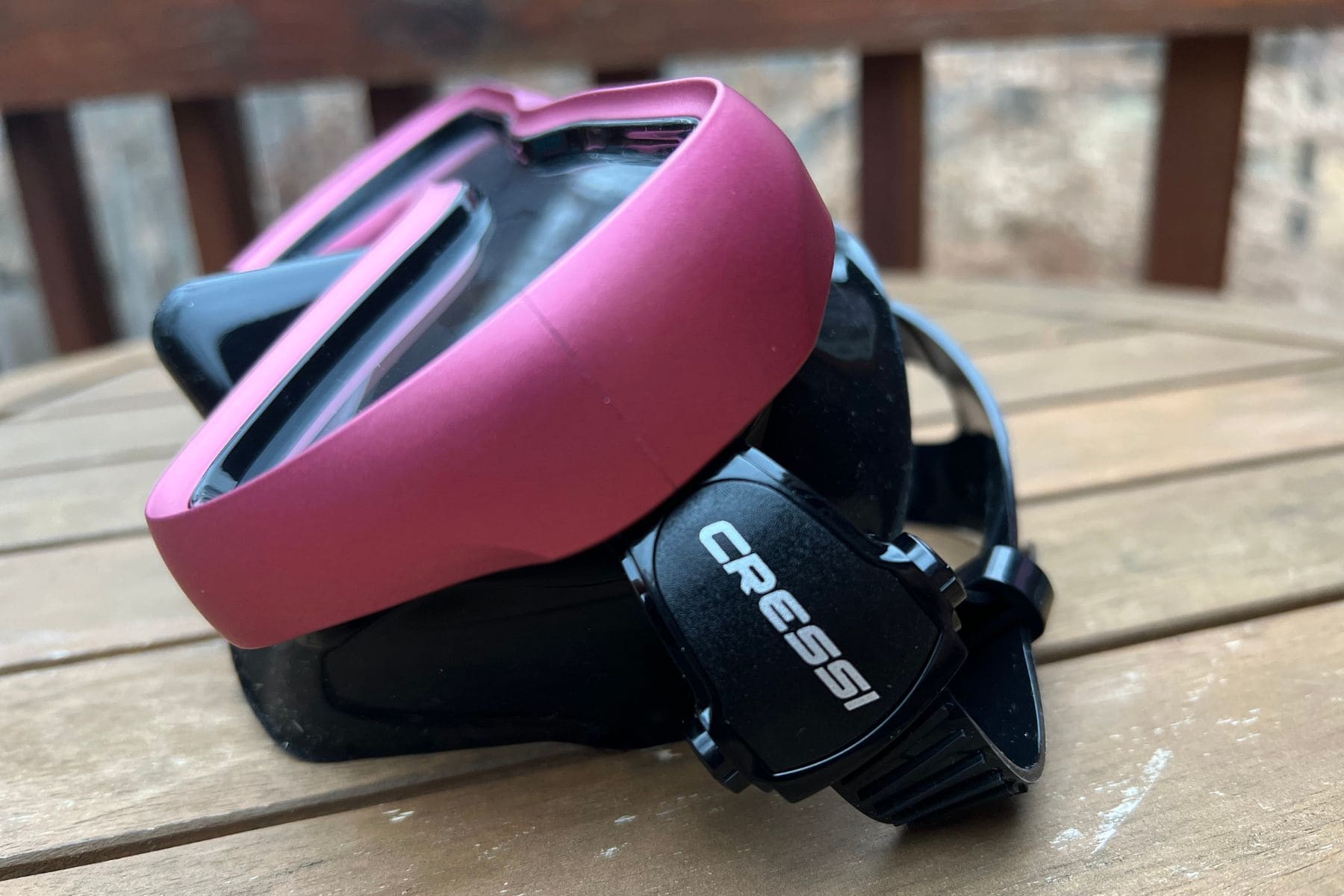Close-up of the Cressi A1 mask on a wooden table showing the side buckle and black skirt