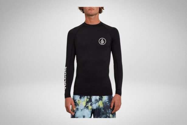 Man in a black Volcom long sleeve rash guard with circle stone logo and printed boardshorts