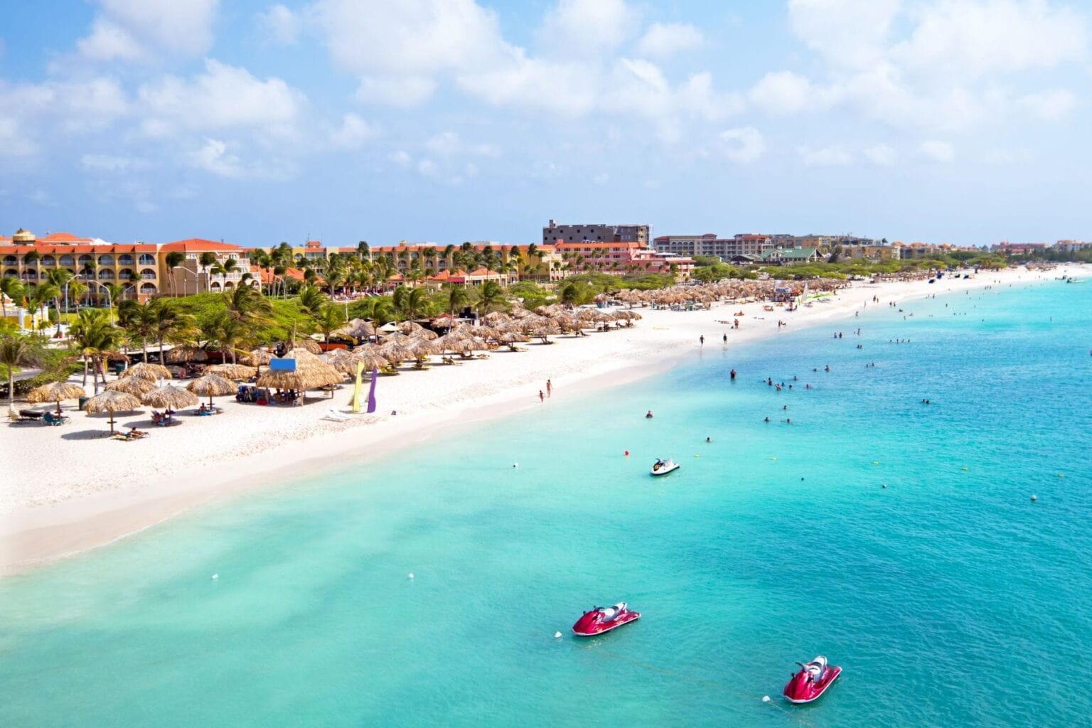 Palm-thatched umbrellas line the white sand shore of Eagle Beach in Aruba