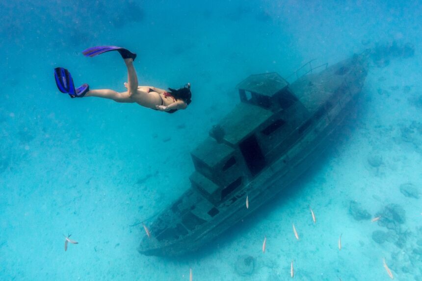 Tugboat Wreck Snorkeling Site Snorkeler swims fins-first over a sunken tugboat wreck