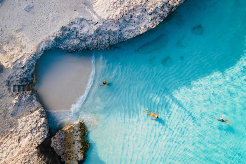 Snorkeling Cove In Aruba Aerial view of swimmers in a clear turquoise pool along Aruba's rocky coast
