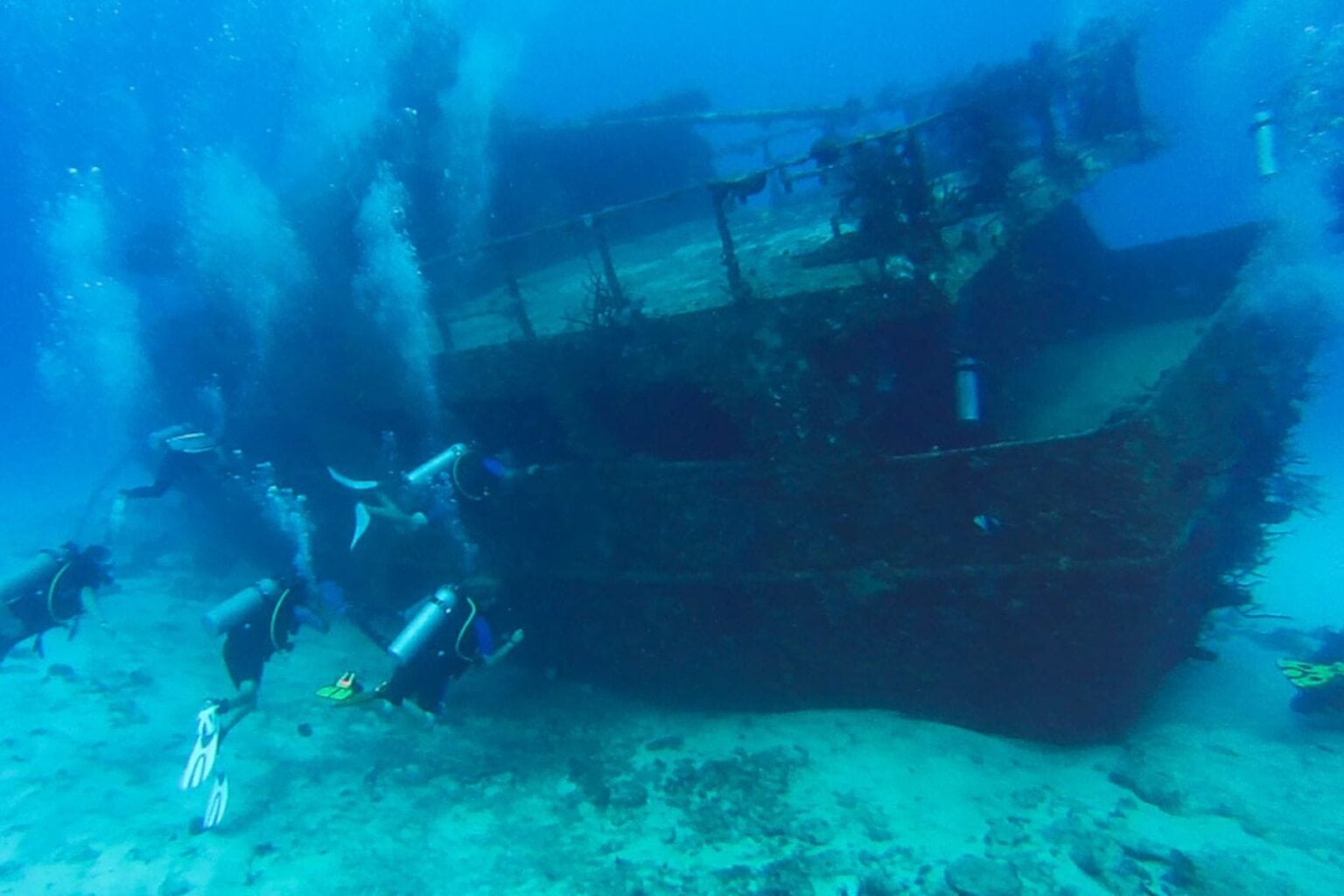 Divers swimming around the sunken Mama Vina shipwreck