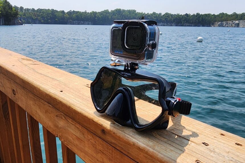 Octomask with a GoPro in its dive housing mounted on top, set on a dock rail above the water