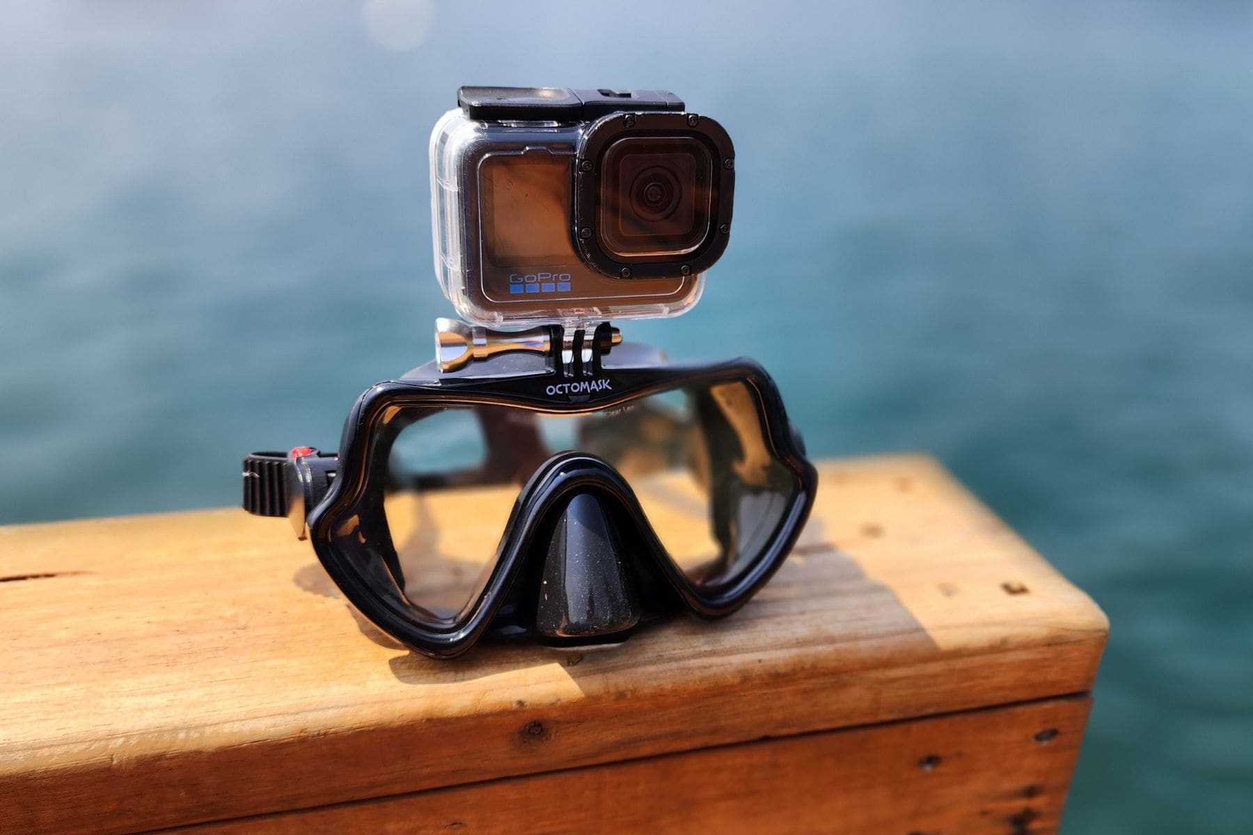 Octomask frameless mask with a GoPro mounted on top, resting on a wooden dock above the water