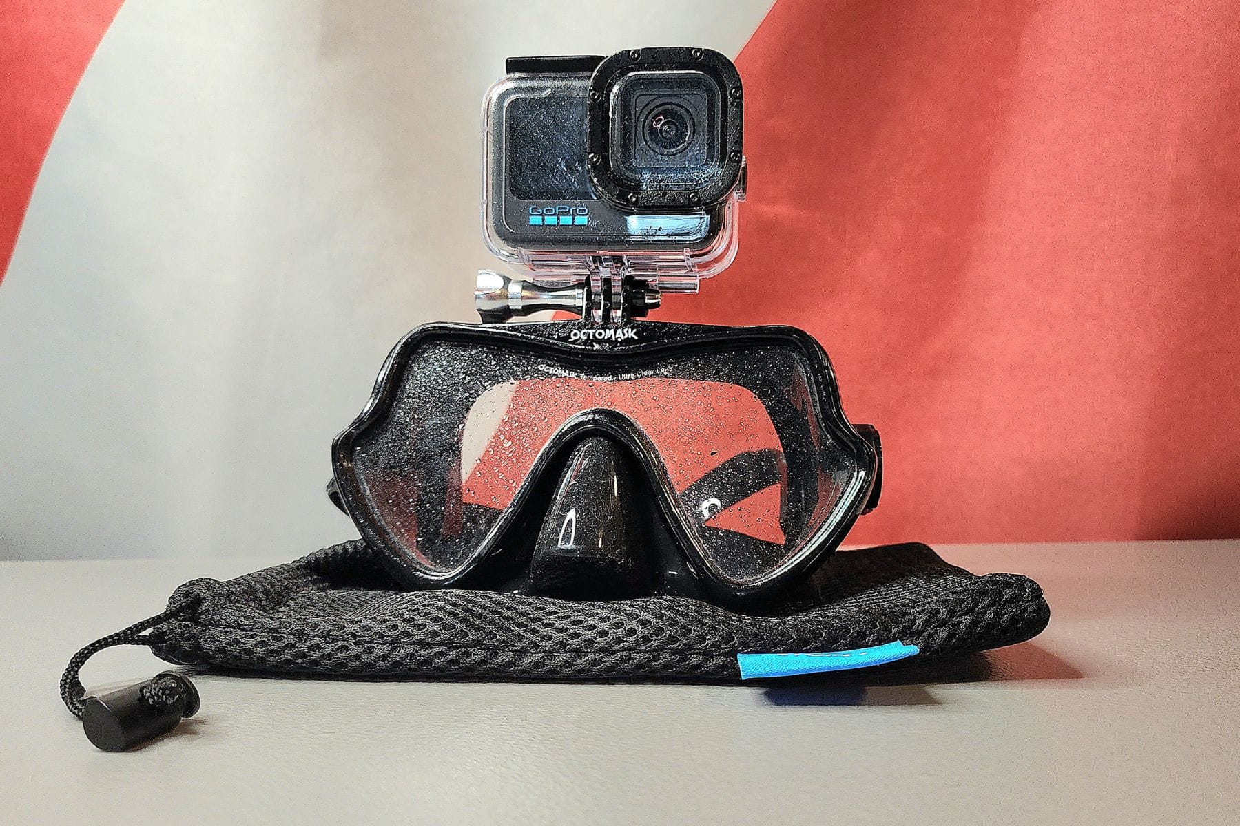 Octomask with a GoPro Hero 11 attached on top, resting on its black mesh bag