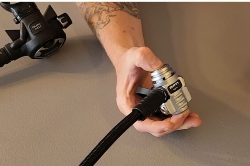 DIVEIN tester holding the compact Mares 62X first stage in one hand to show its size