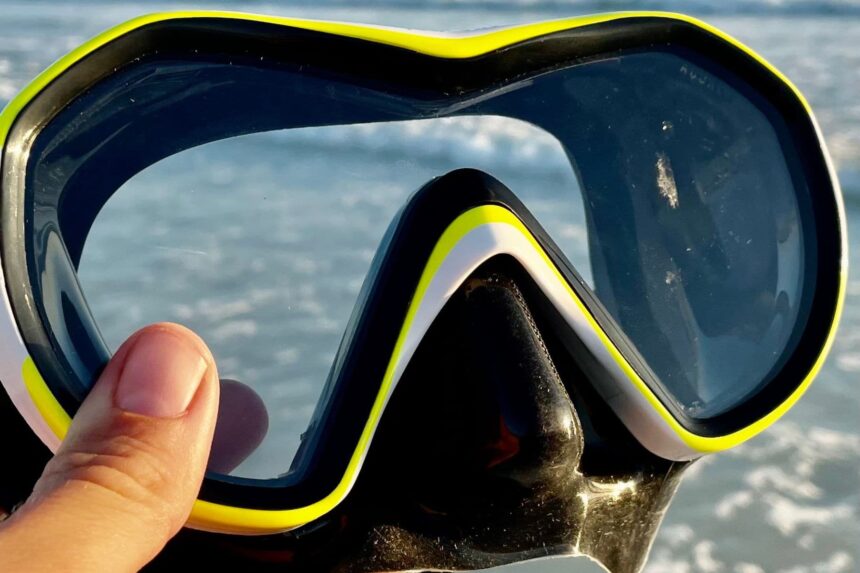 Close-up of the Aqualung Reveal X1 single lens held up in front of the sea
