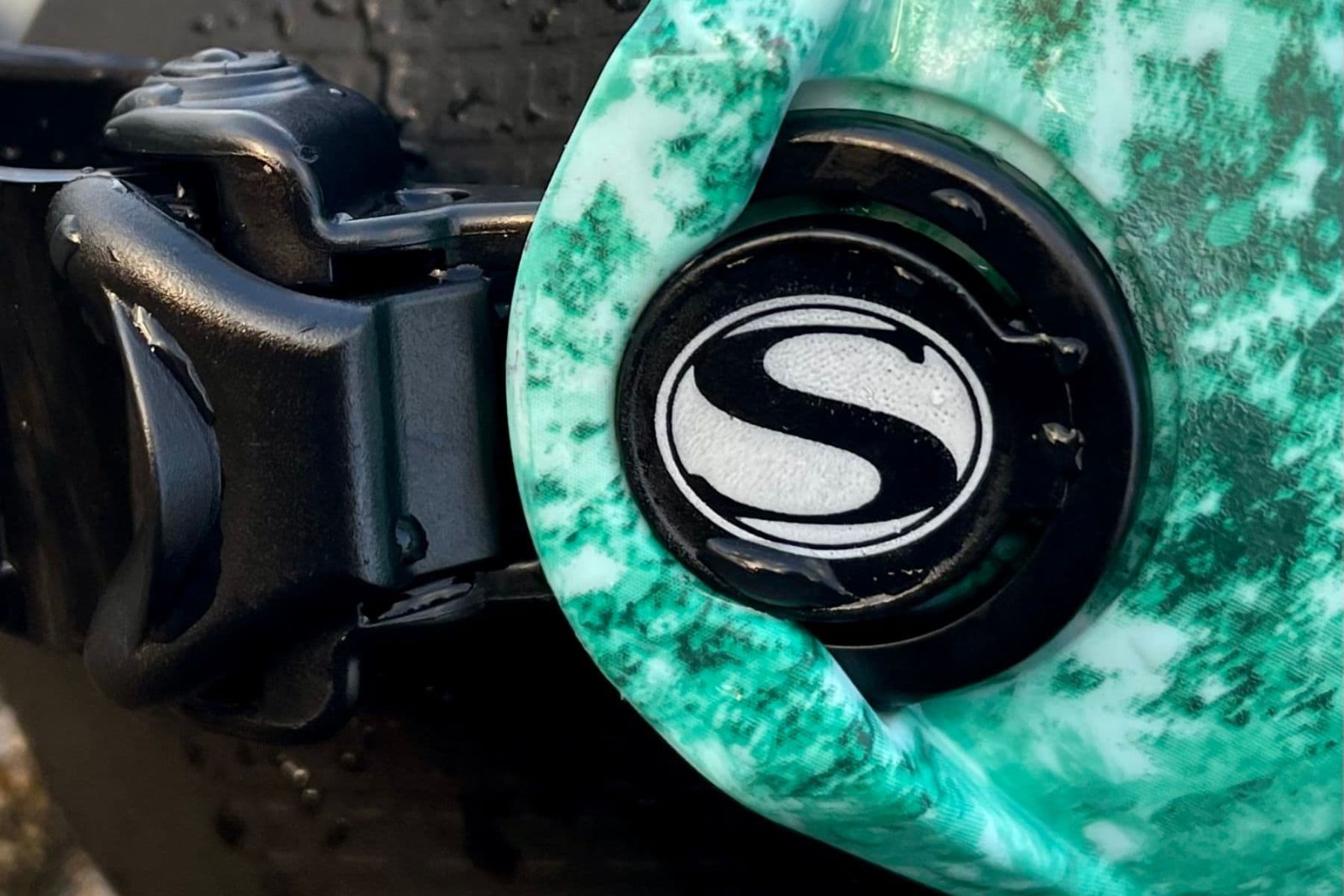 Close-up of the Sherwood Cruz quick-connect buckle beside the mint green skirt and S logo