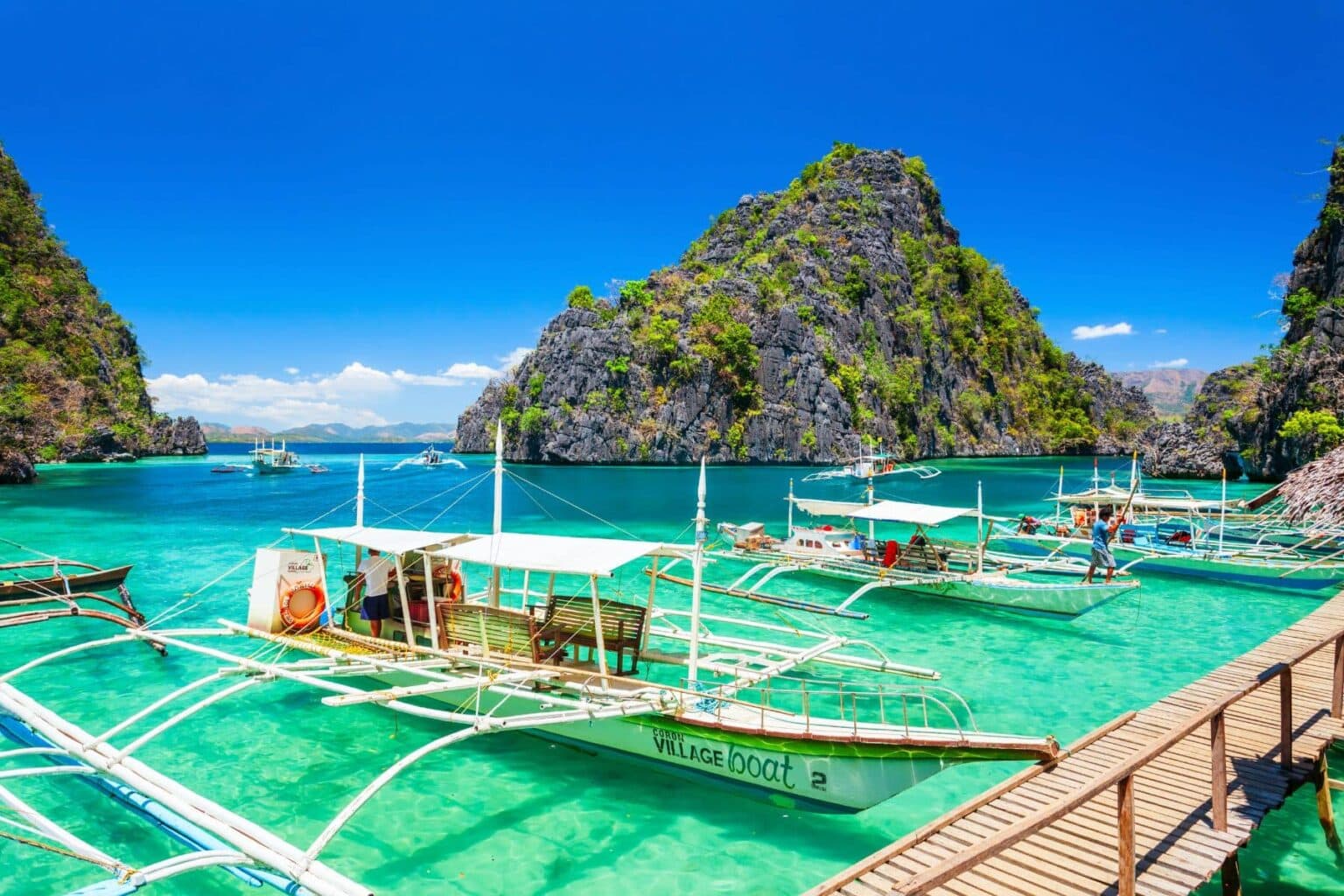 Traditional outrigger boats moored in the turquoise lagoon of Coron Bay, Philippines