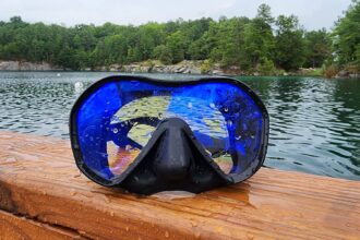 TUSA Zensee Pro mask with its blue UV420 lens, wet on a wooden rail beside a lake