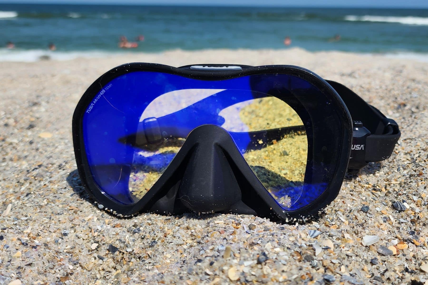TUSA Zensee Pro sitting in shell sand, its blue UV 420 lens facing the camera