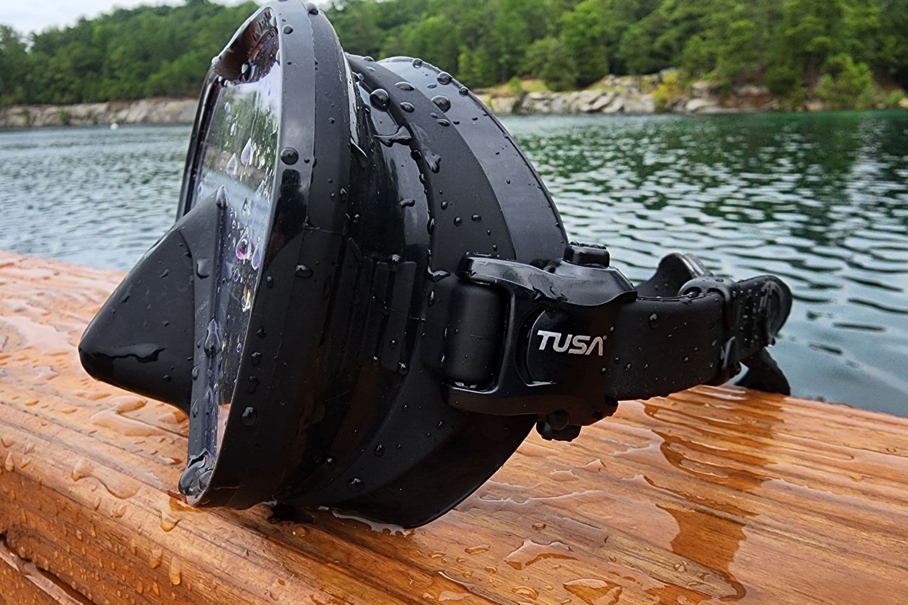 Side view of the TUSA Zensee Pro on a wet wooden rail beside a lake
