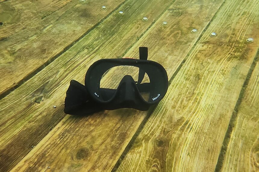 Hollis M1 mask lying on submerged wooden planks in green water