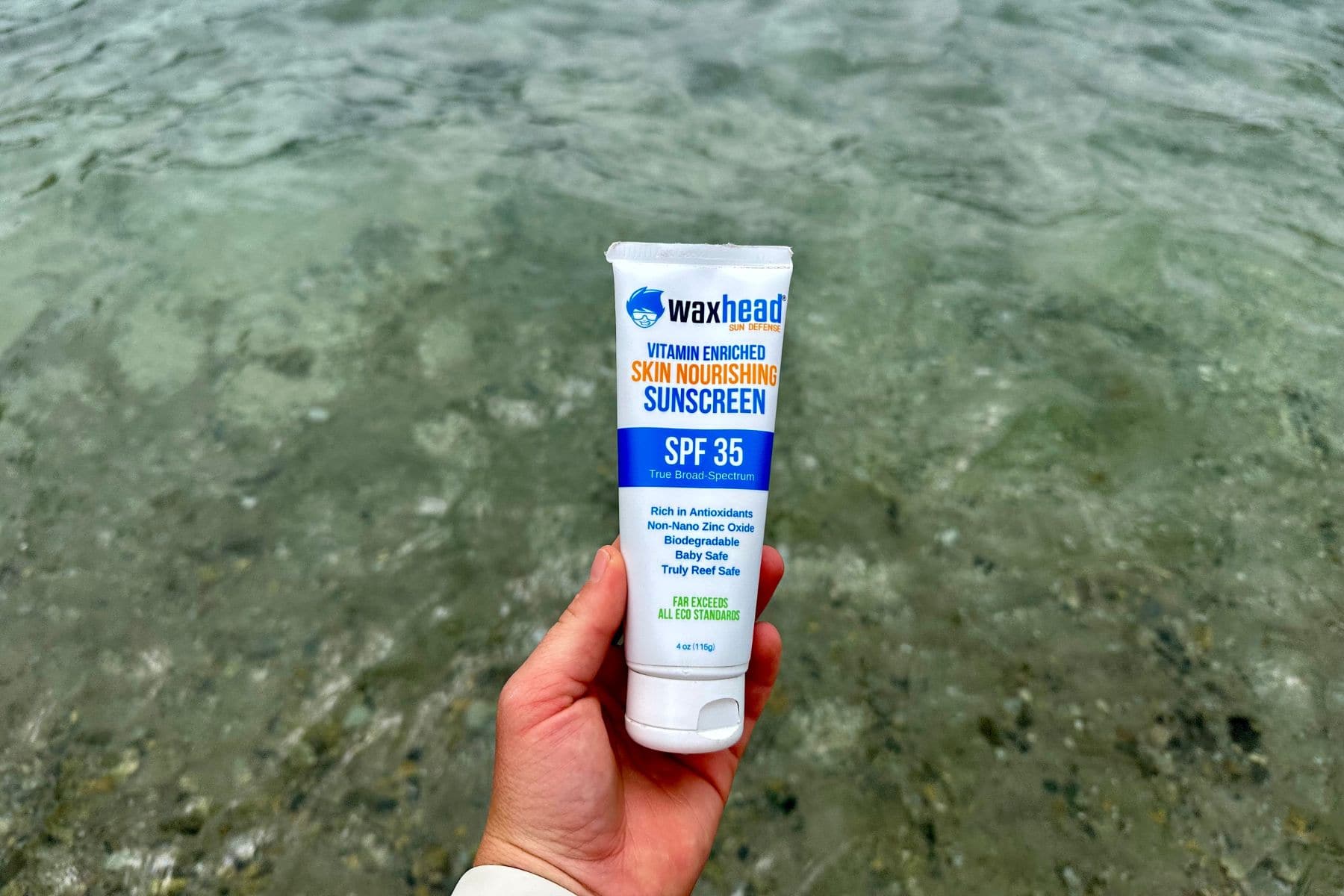 Waxhead Skin Nourishing Sunscreen SPF 35 tube held above clear shallow water