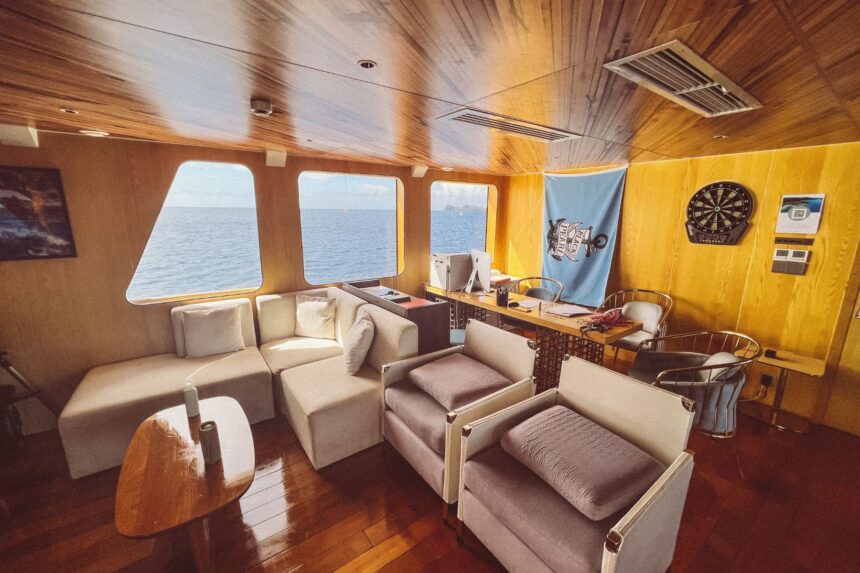 Wood paneled indoor lounge aboard the Black Pearl Explorer with sofas and dartboard