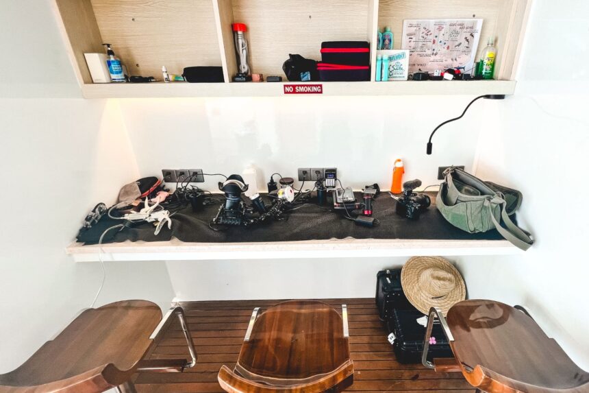 Camera charging station with dive gear and hats on the Black Pearl Explorer's deck