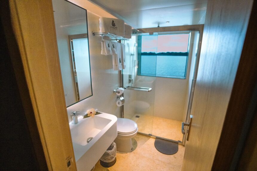 En suite bathroom aboard the Black Pearl Explorer with glass shower and sunset view