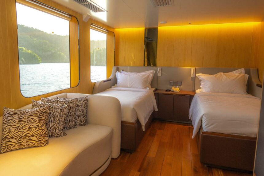 Twin cabin with zebra print pillows and a lounge seat aboard the Black Pearl Explorer