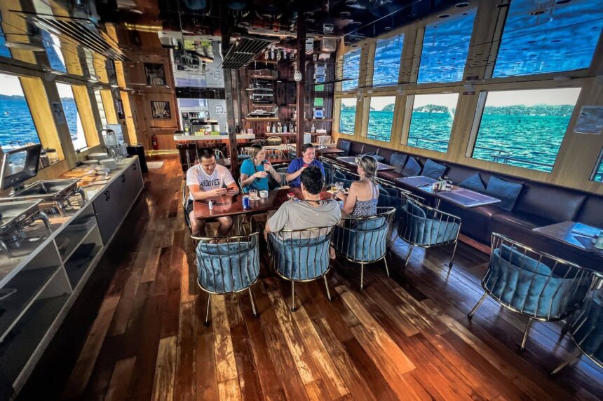 Guests seated at a table in the Black Pearl Explorer's dining lounge overlooking the sea